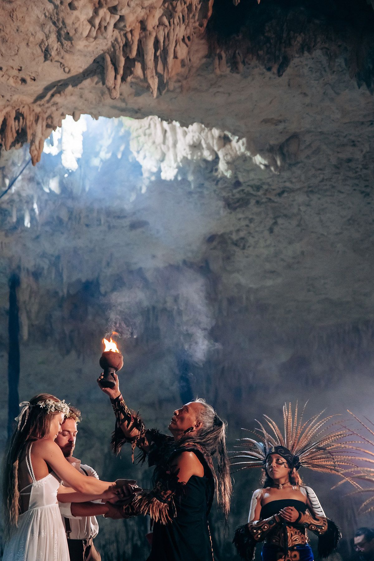 Ancient Mayan ritual performed in atmospheric cave setting with natural light beams illuminating traditional dancers.