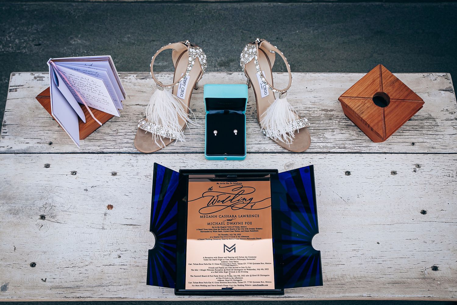 Wedding invitation suite displayed on white wooden surface with elegant navy and brown paper elements.