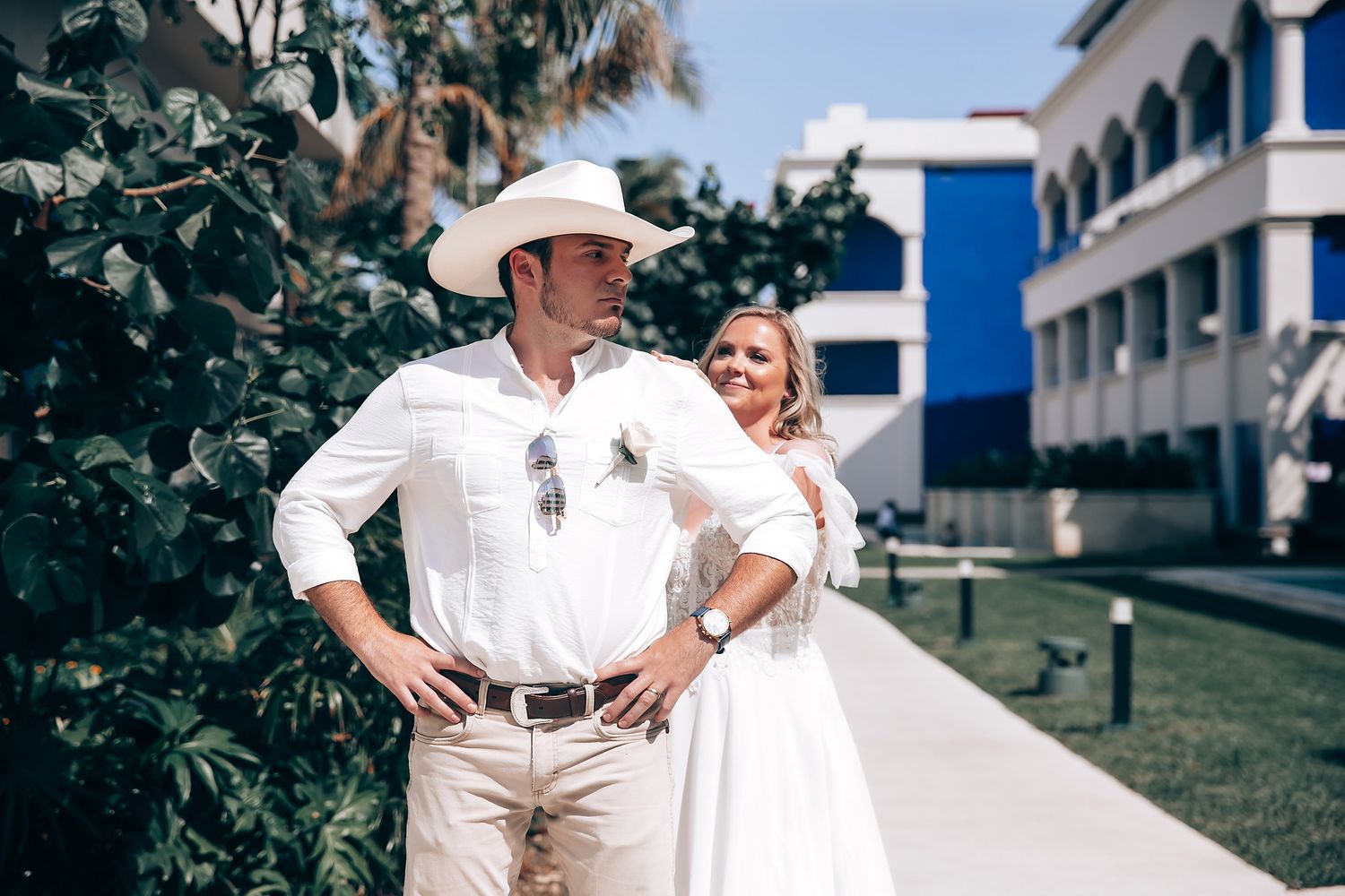 People in white outfits sharing romantic moments outdoors near a building.