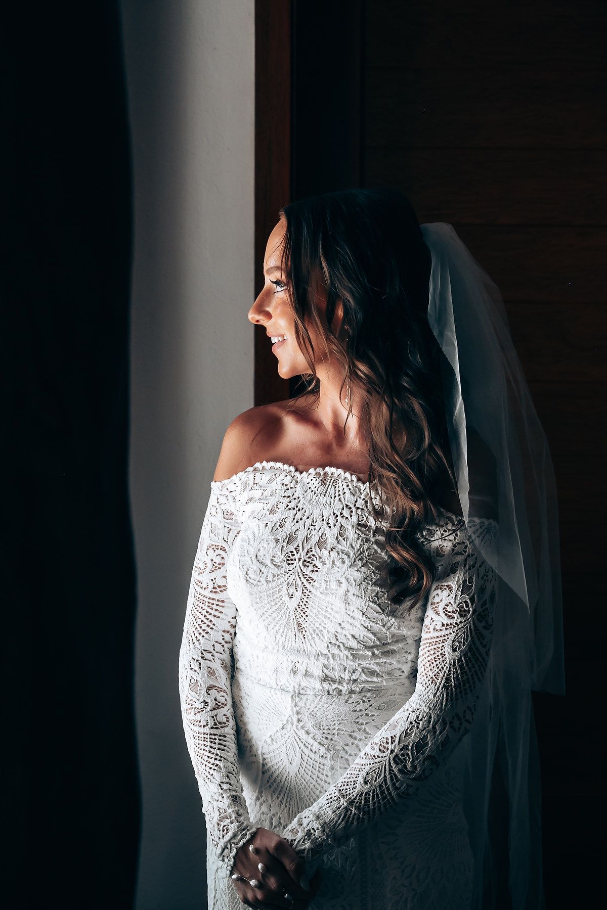 Artistic side view of an elegant white lace wedding dress in dramatic lighting.