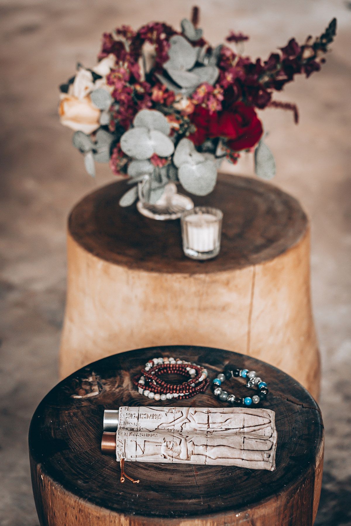 White sage smudge stick with crystals and floral arrangements displayed on rustic wooden surfaces with candles.