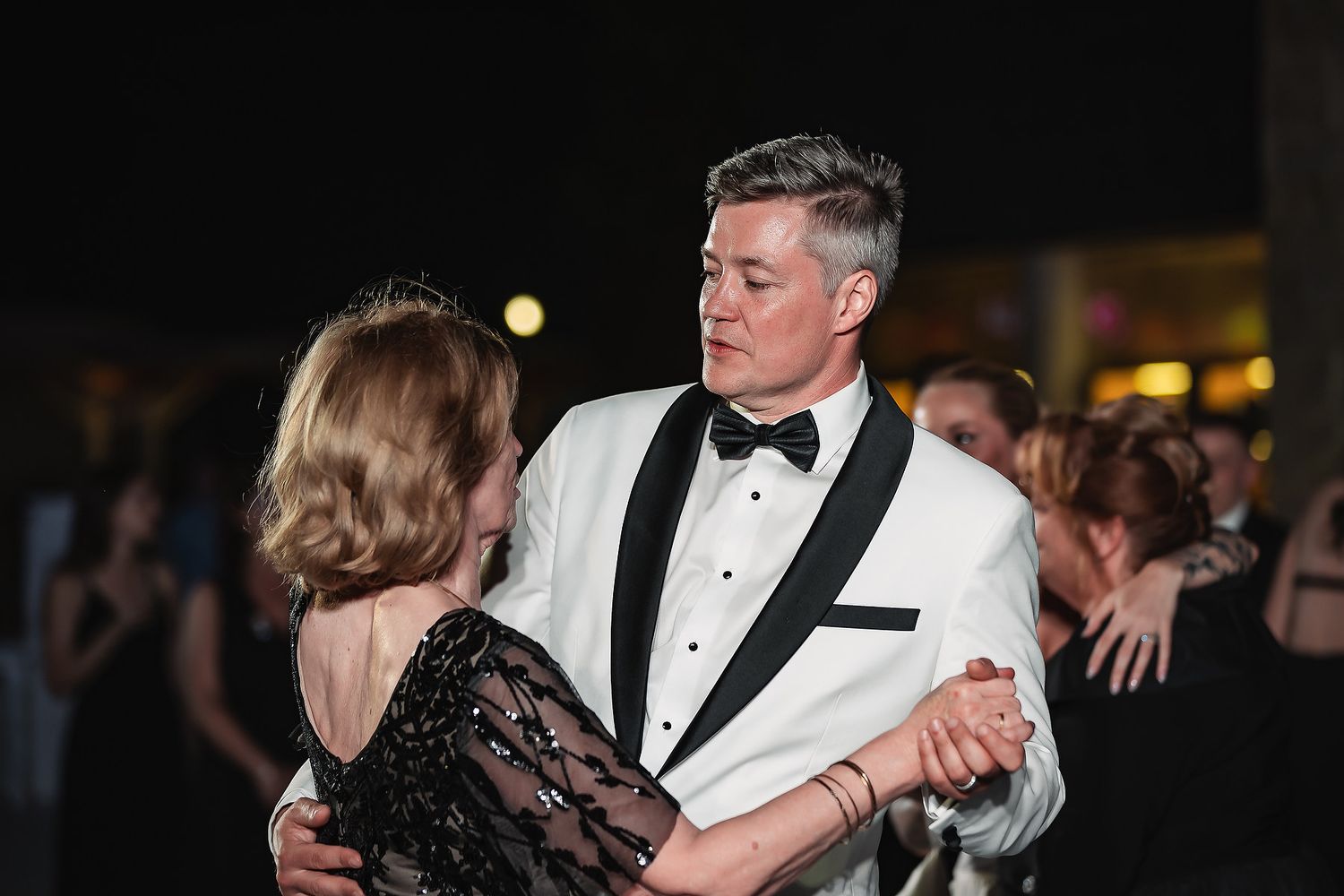 Elegant dance at wedding reception with groom in white dinner jacket with black lapels.