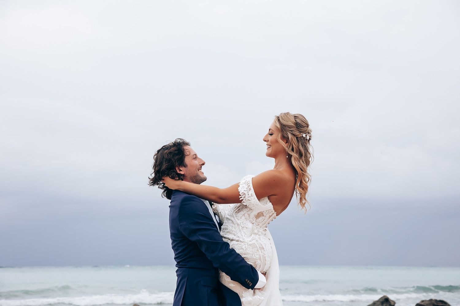 Romantic beach photoshoot with couple dancing by the ocean waves.