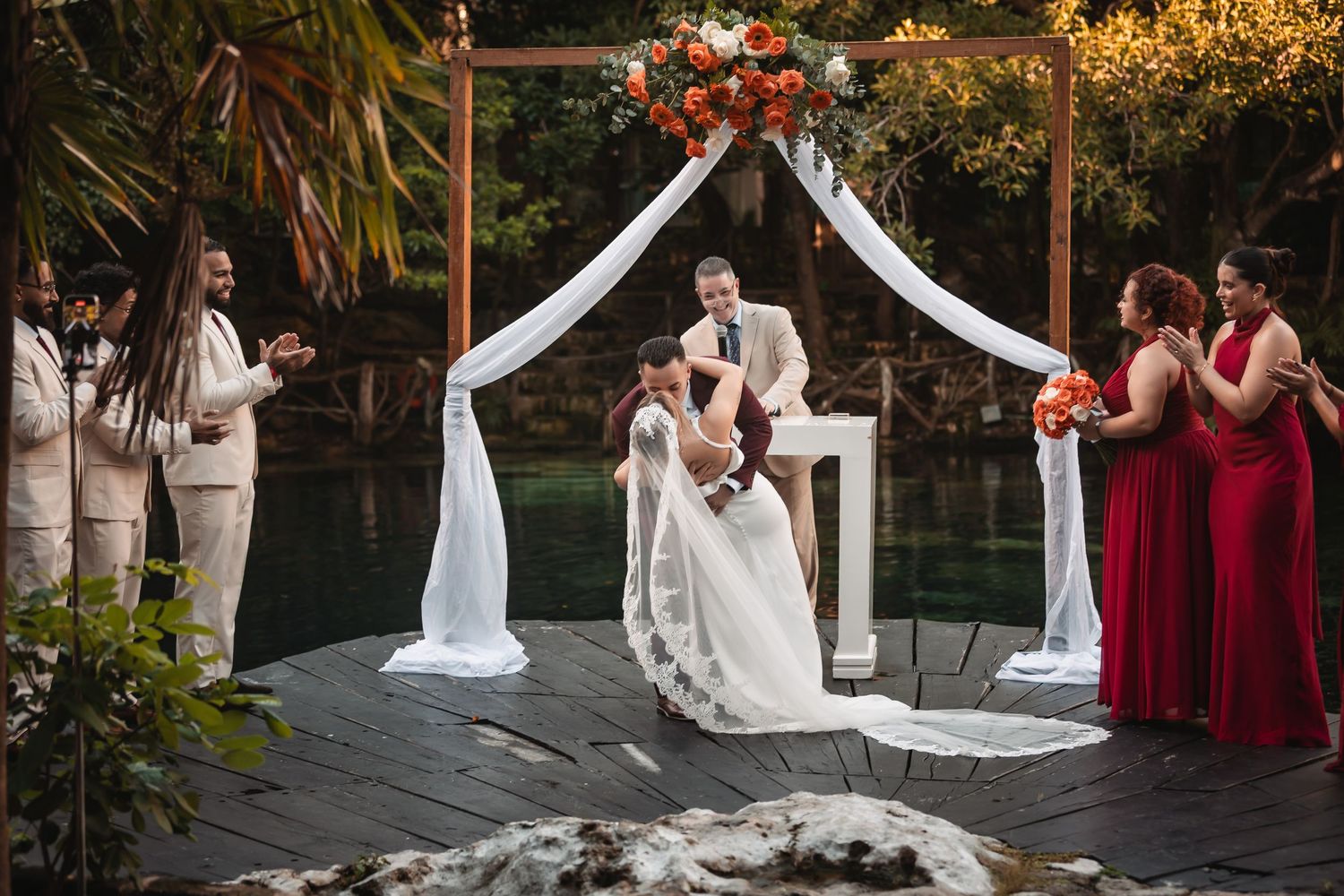 Outdoor wedding ceremony setup with white chairs and floral arrangements in a garden setting.