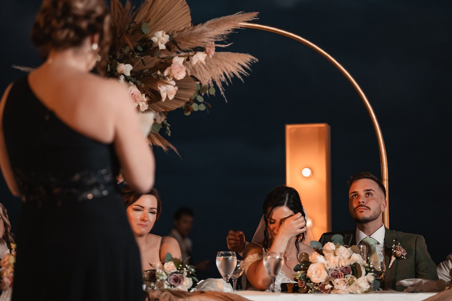 Intimate wedding moments captured under string lights at a beach reception.