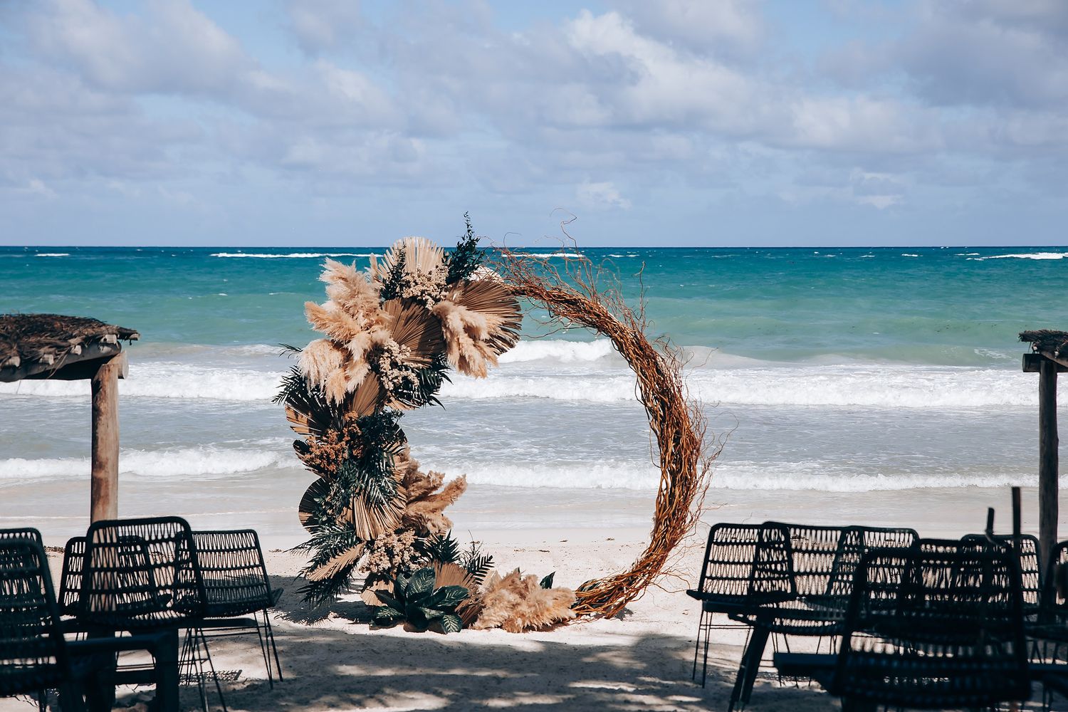 Beach lounge chairs arranged along turquoise ocean shoreline under palm trees.