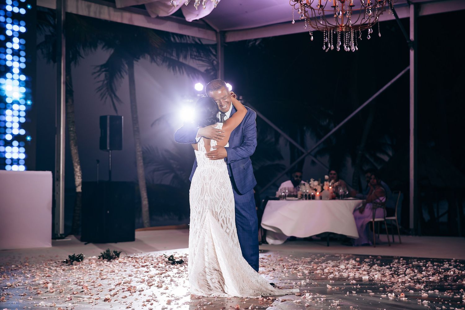 A couple shares their first dance at a wedding reception under elegant crystal chandeliers.
