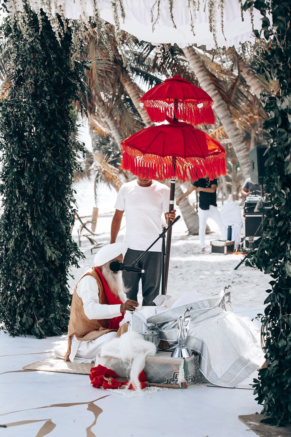 Red parasol and white attire create romantic wedding scene in snowy tropical setting.