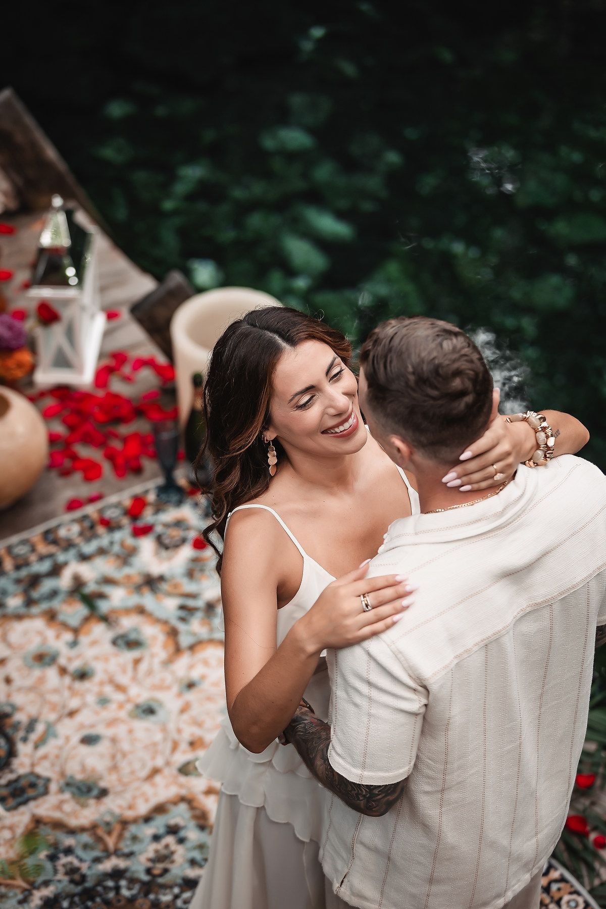 Couple in white embracing during an intimate outdoor photoshoot with rose petals.