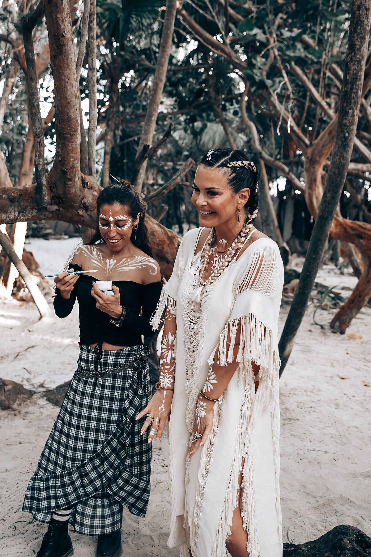 Friends in white and casual attire share laughs during a beach celebration.