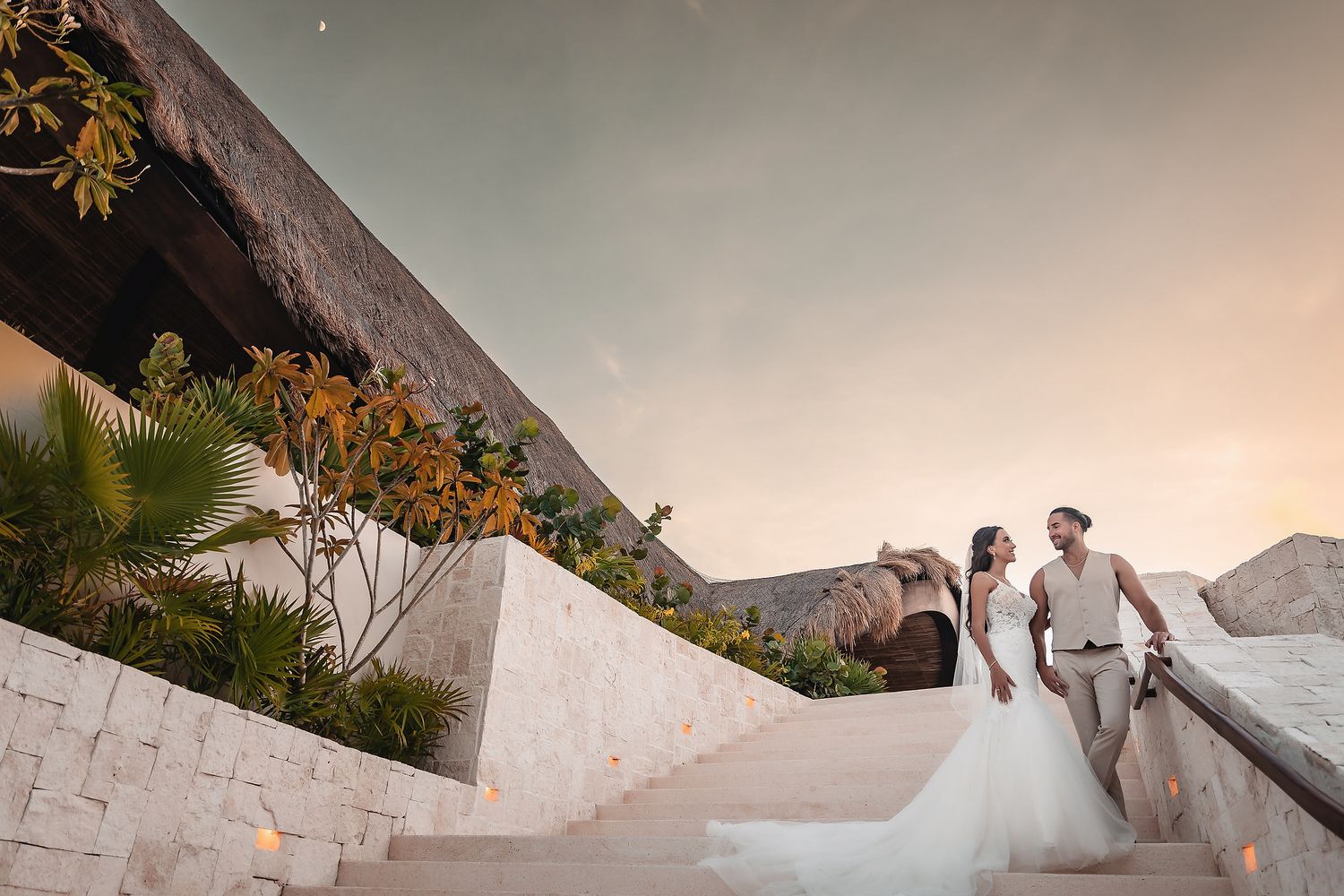 Bride and groom share a romantic moment on stone steps at sunset during their destination wedding.