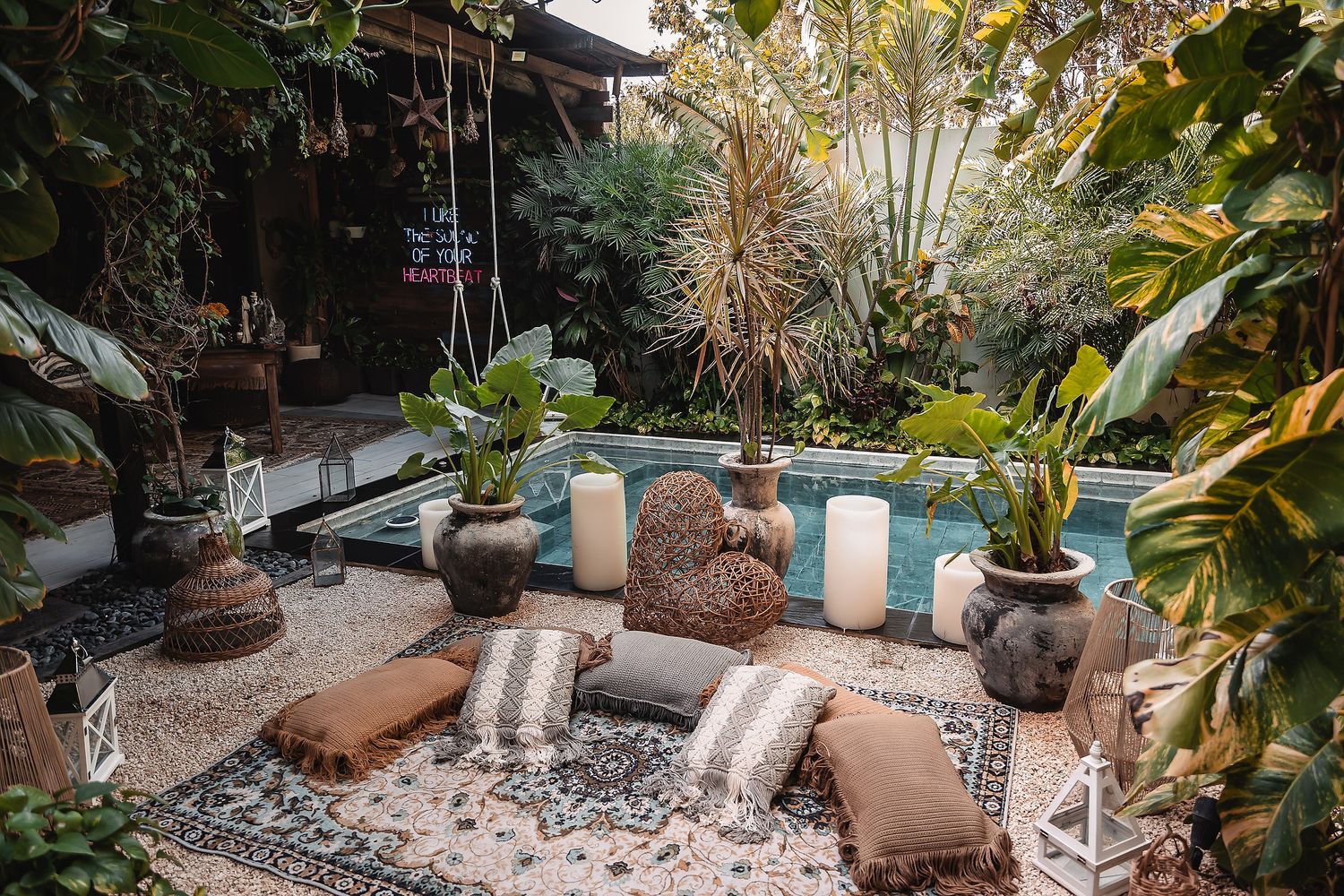 Tropical garden lounge area with striped cushions and decorative pots.