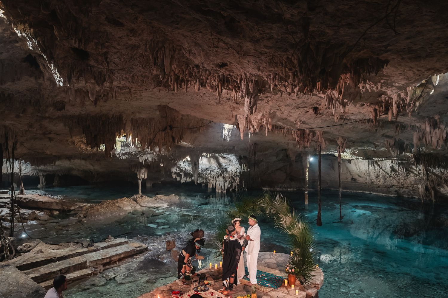Wedding celebration in a natural cave setting with crystal clear blue waters and atmospheric lighting.