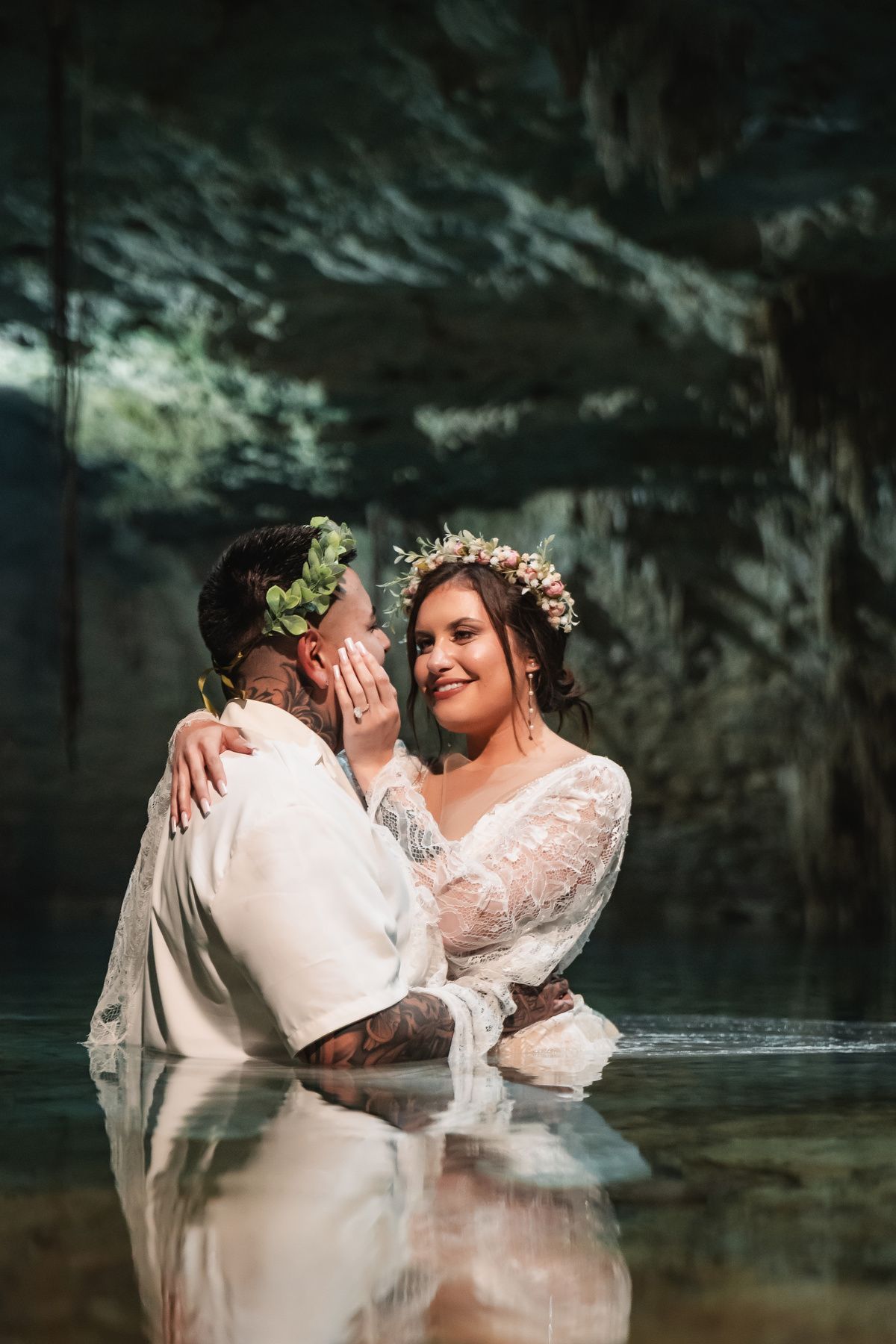 A tender moment captured between newlyweds in a mystical cenote with dramatic cave walls.