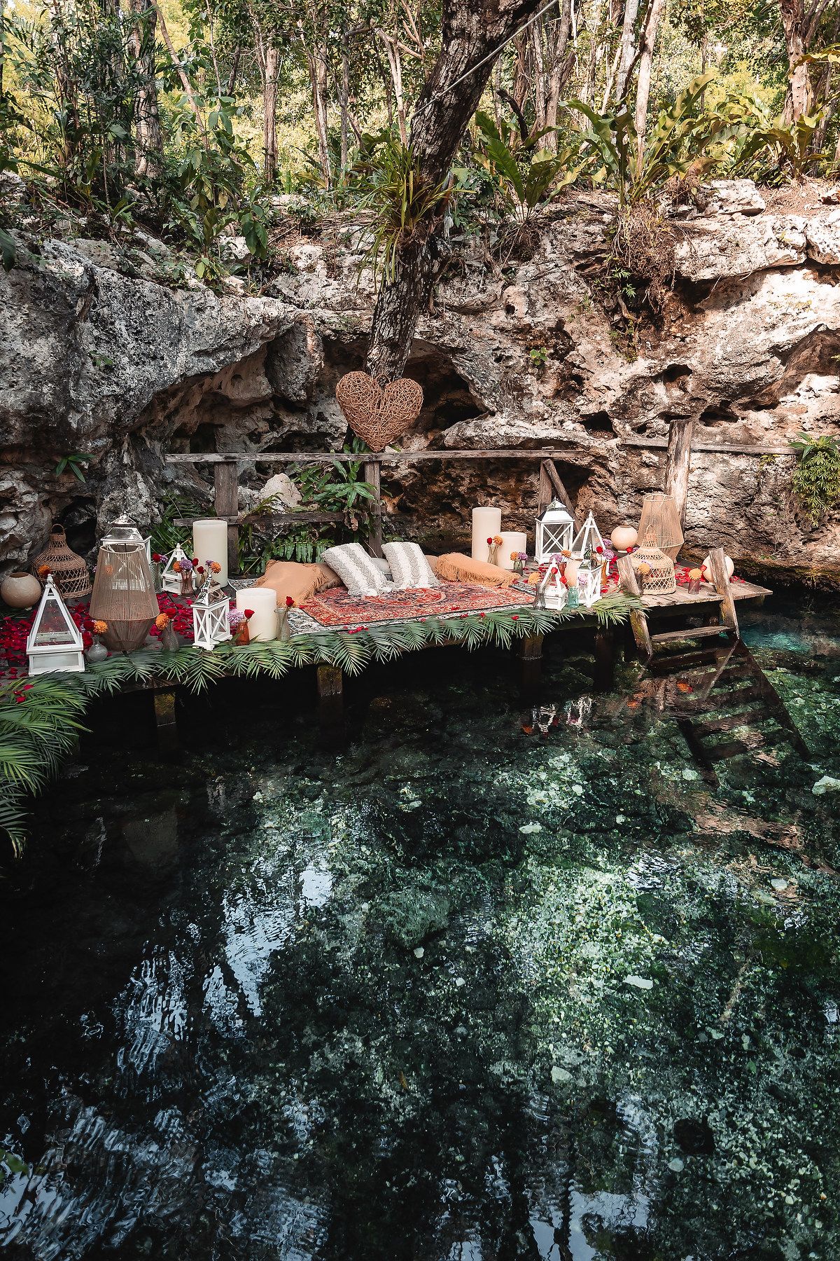 Luxurious picnic spread with decorative elements set up along a natural cenote's edge.