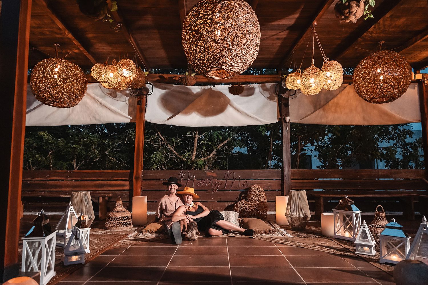 Outdoor covered deck with decorative woven light fixtures and comfortable seating.
