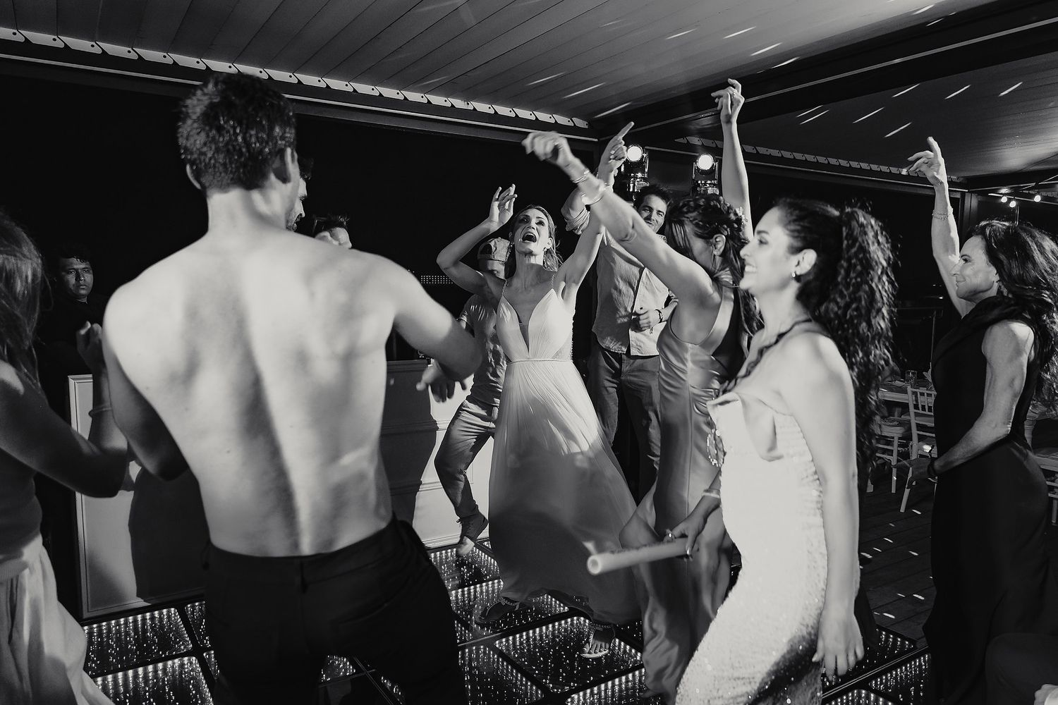 Black and white photo showing silhouettes of people dancing and celebrating at a party.