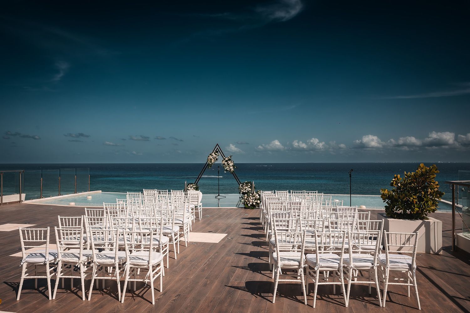 White chairs arranged in rows for a beachfront wedding ceremony with ocean views.