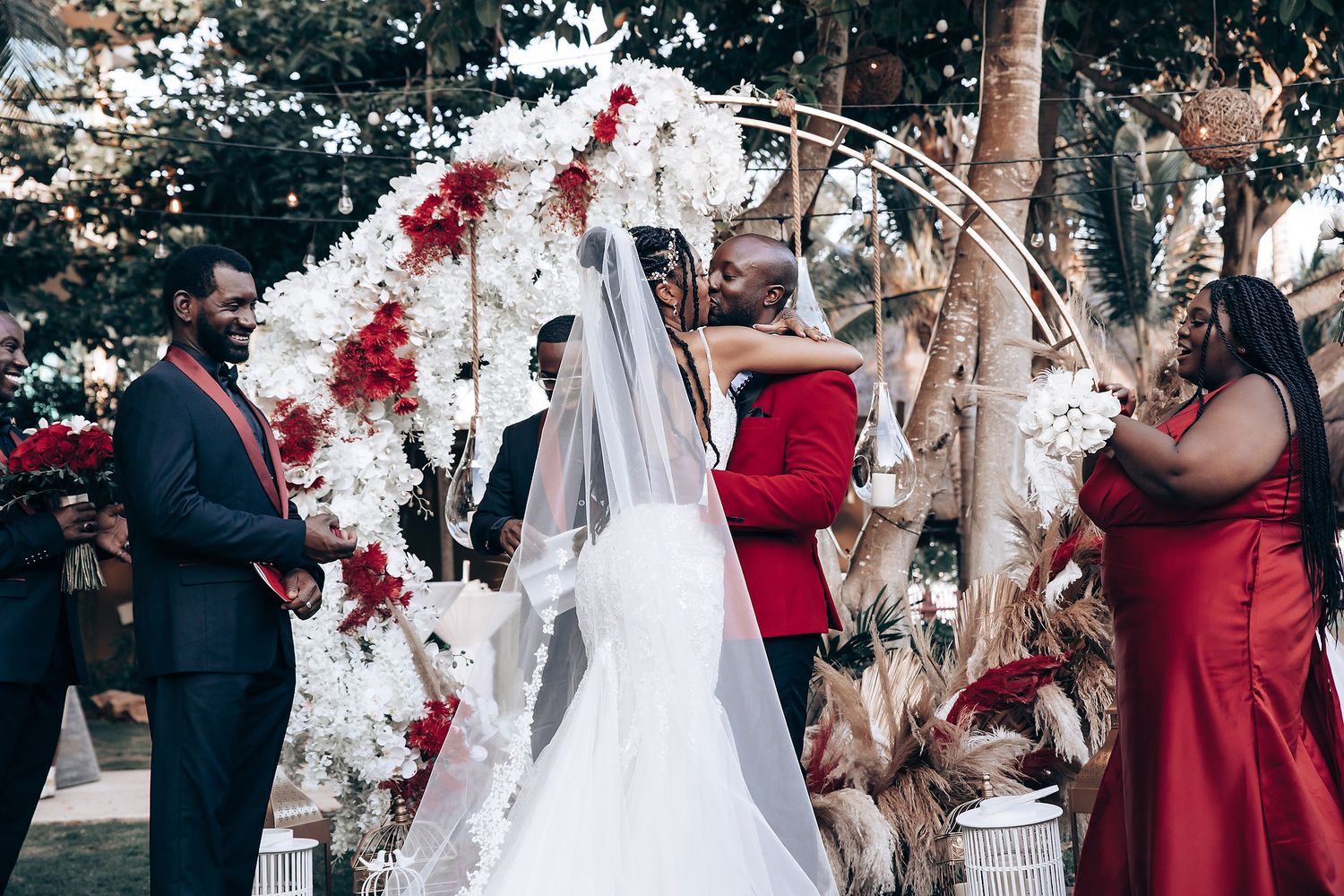 Wedding party celebrates with confetti and rose petals during outdoor ceremony in garden setting.