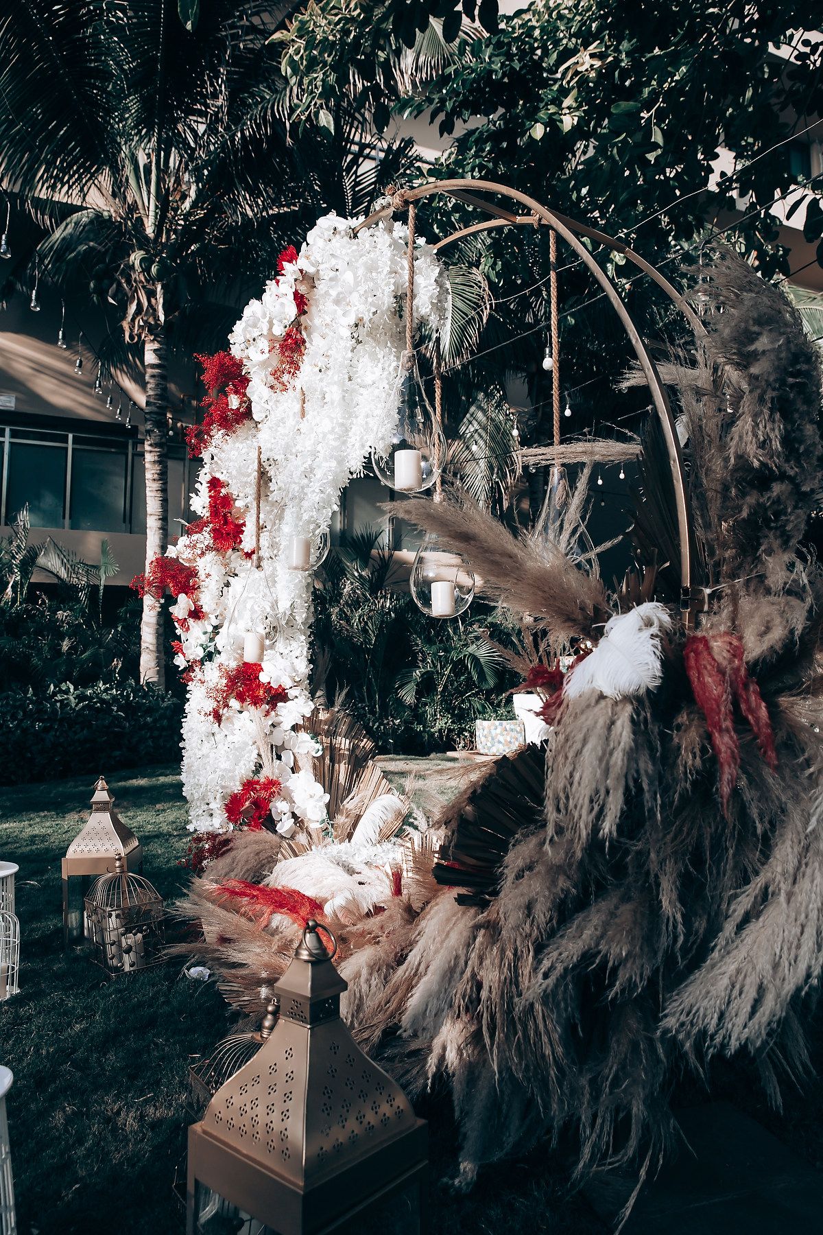 Artistic installation featuring dried pampas grass and red floral elements arranged in a dramatic moody display.