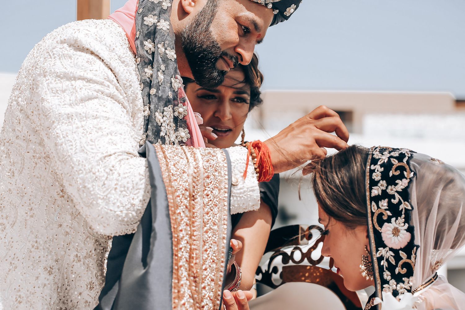 A person in traditional Indian wedding attire holds a glass while seated during a cultural ceremony.