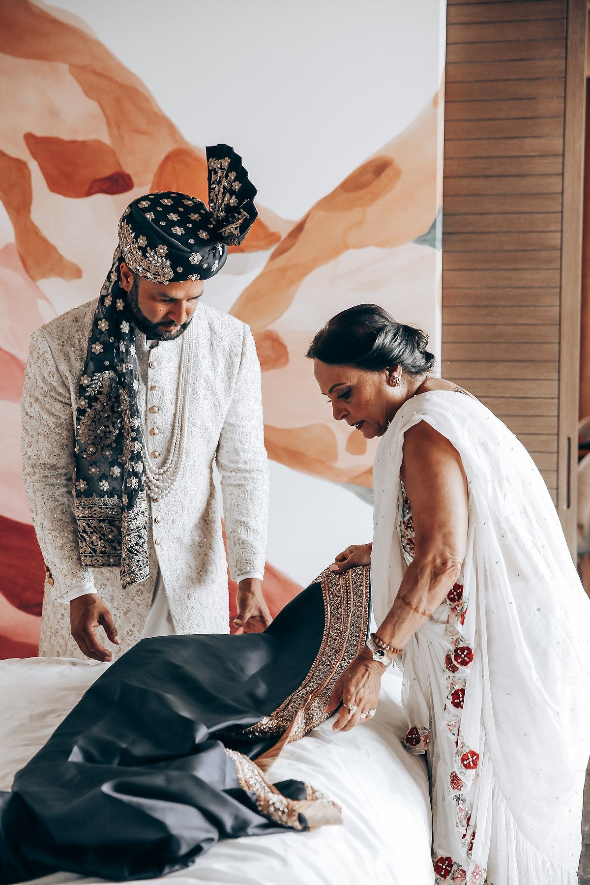 A sequence of four photos showing a couple in white traditional outfits interacting with a black dog.