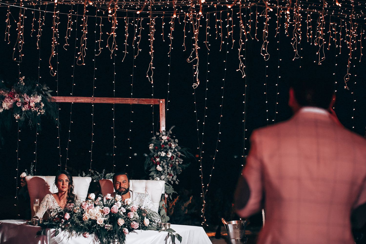 A couple shares their first dance at a wedding reception with sparkling lights in the background.