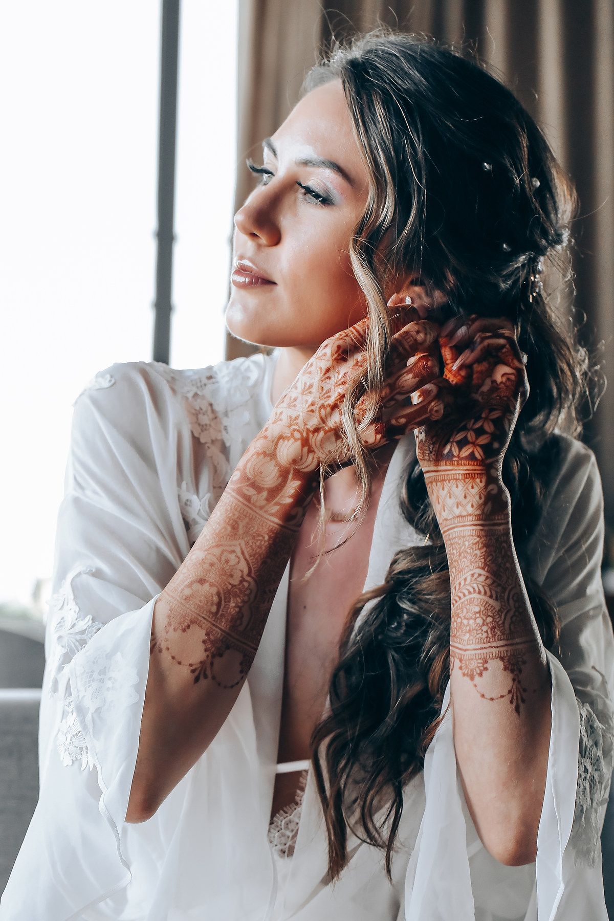 A series of artistic photos showing a person with henna-adorned hands in contemplative poses wearing white.