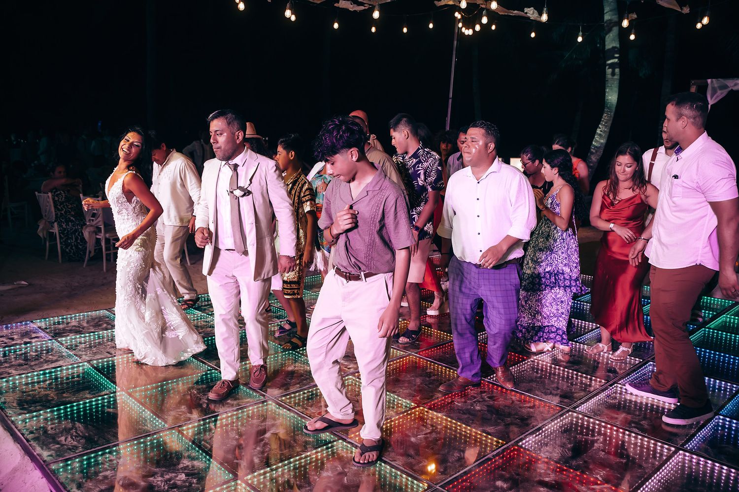 Party guests dancing on an illuminated LED dance floor at a nighttime celebration event.