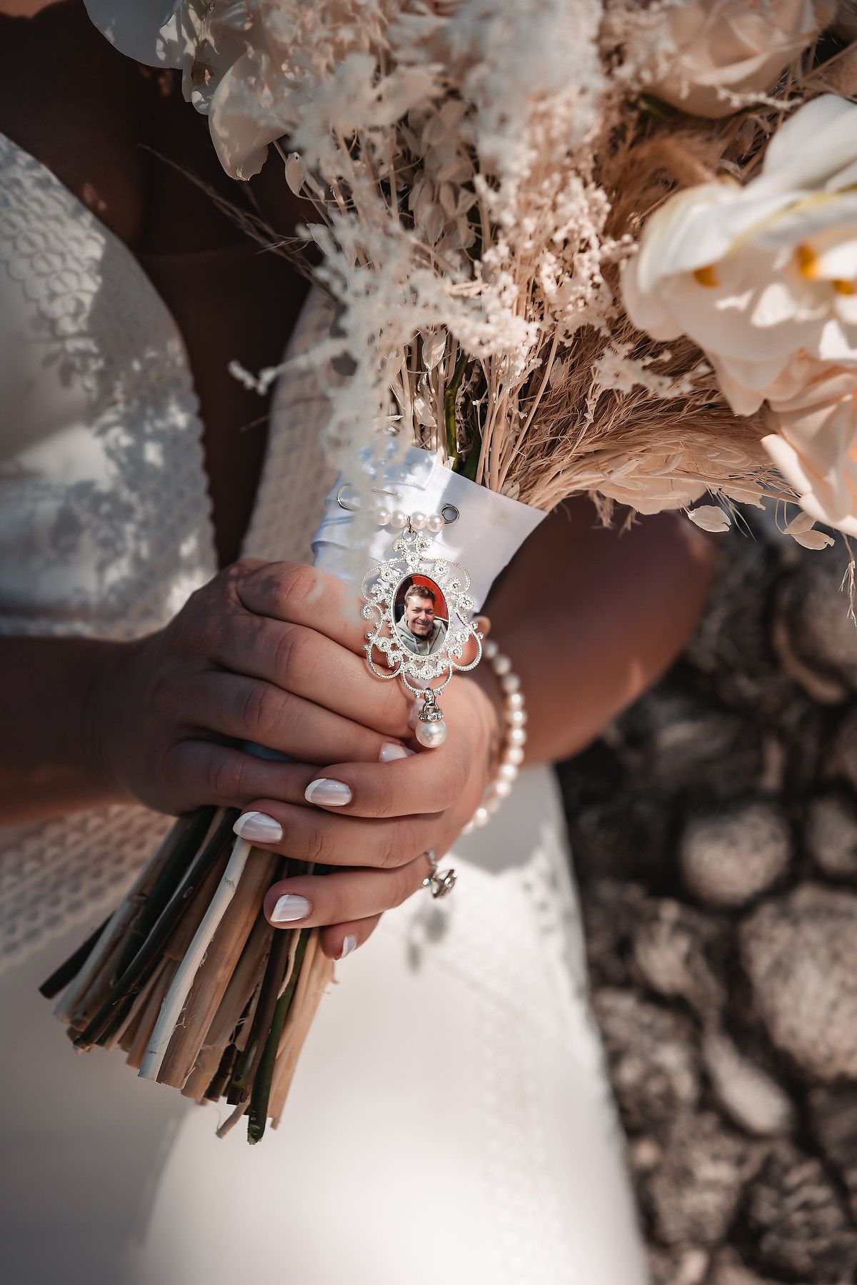 Close-up of elegant bridal hands holding a white wedding bouquet with delicate manicured nails.