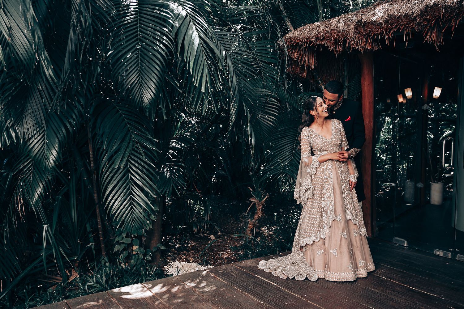 Elegant wedding photo shoot in a tropical garden with palm fronds and wooden deck.
