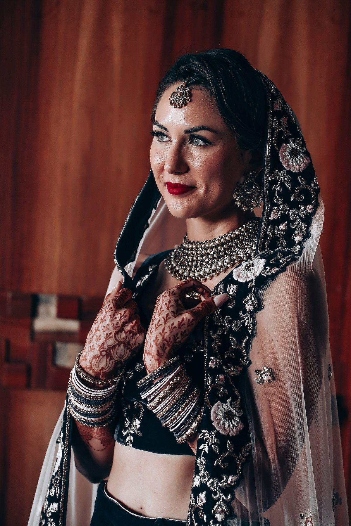 Close-up details of intricate henna designs and jewelry on South Asian bride.