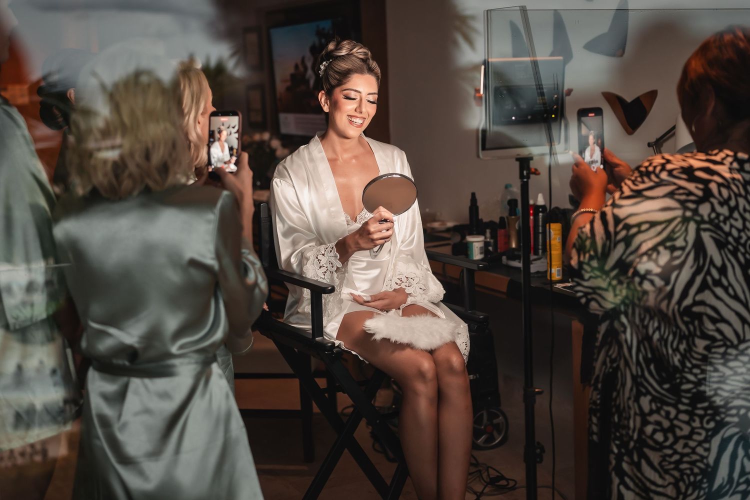 Getting ready scene with white wedding dress hanging in natural window light.