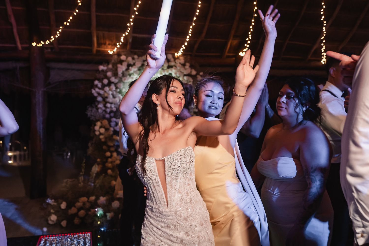 Wedding reception dance floor with festive string lights and guests celebrating.
