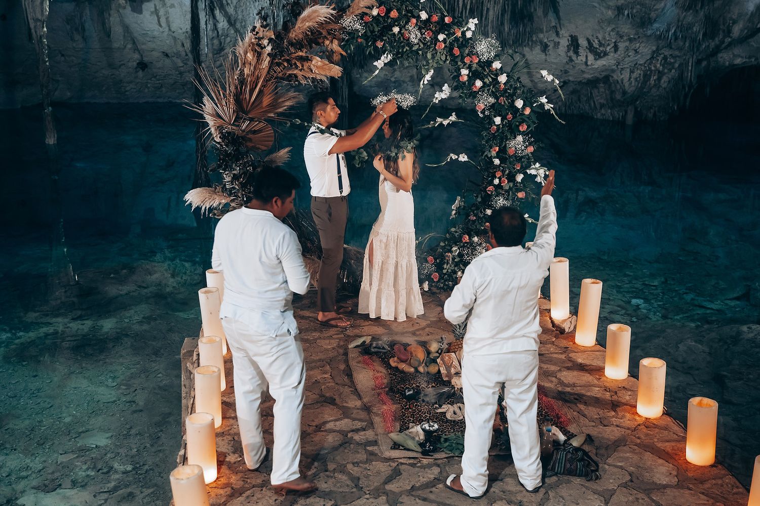 A romantic outdoor wedding ceremony at night with paper lanterns lining a pathway through the trees.