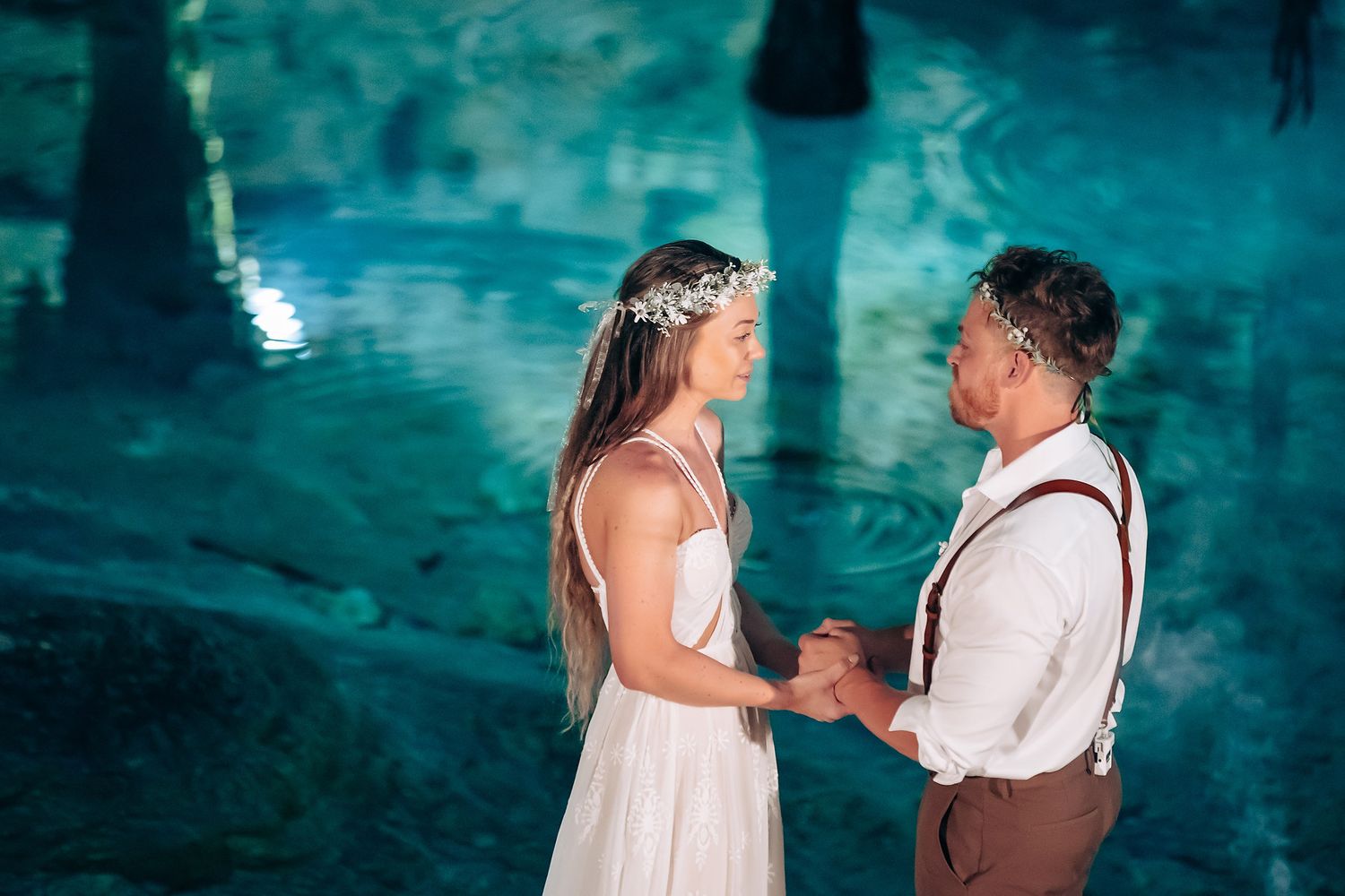 Intimate cave wedding ceremony with turquoise waters reflecting ethereal blue light throughout the natural cavern.