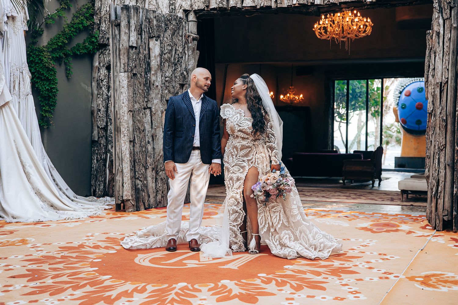 A couple celebrates at their rustic wedding venue with a decorative orange carpet and vintage chandelier.