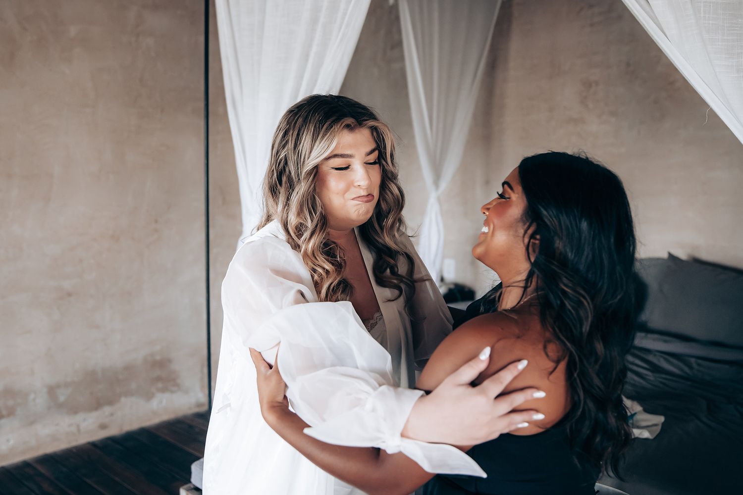 Romantic couple sharing intimate moments in a dimly lit bedroom with white curtains and neutral tones.