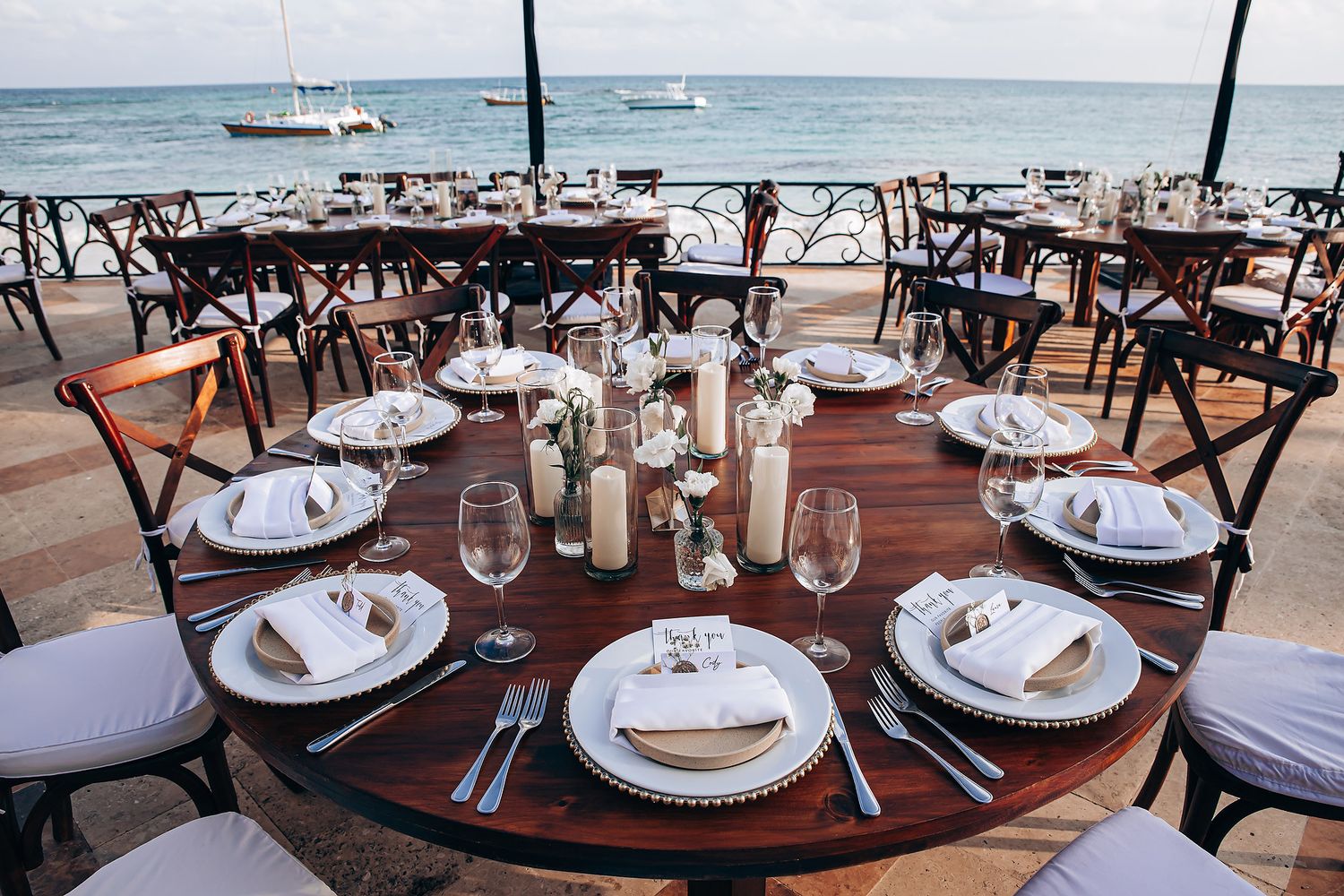 Round dining tables with elegant place settings and wine glasses arranged in an upscale restaurant interior.