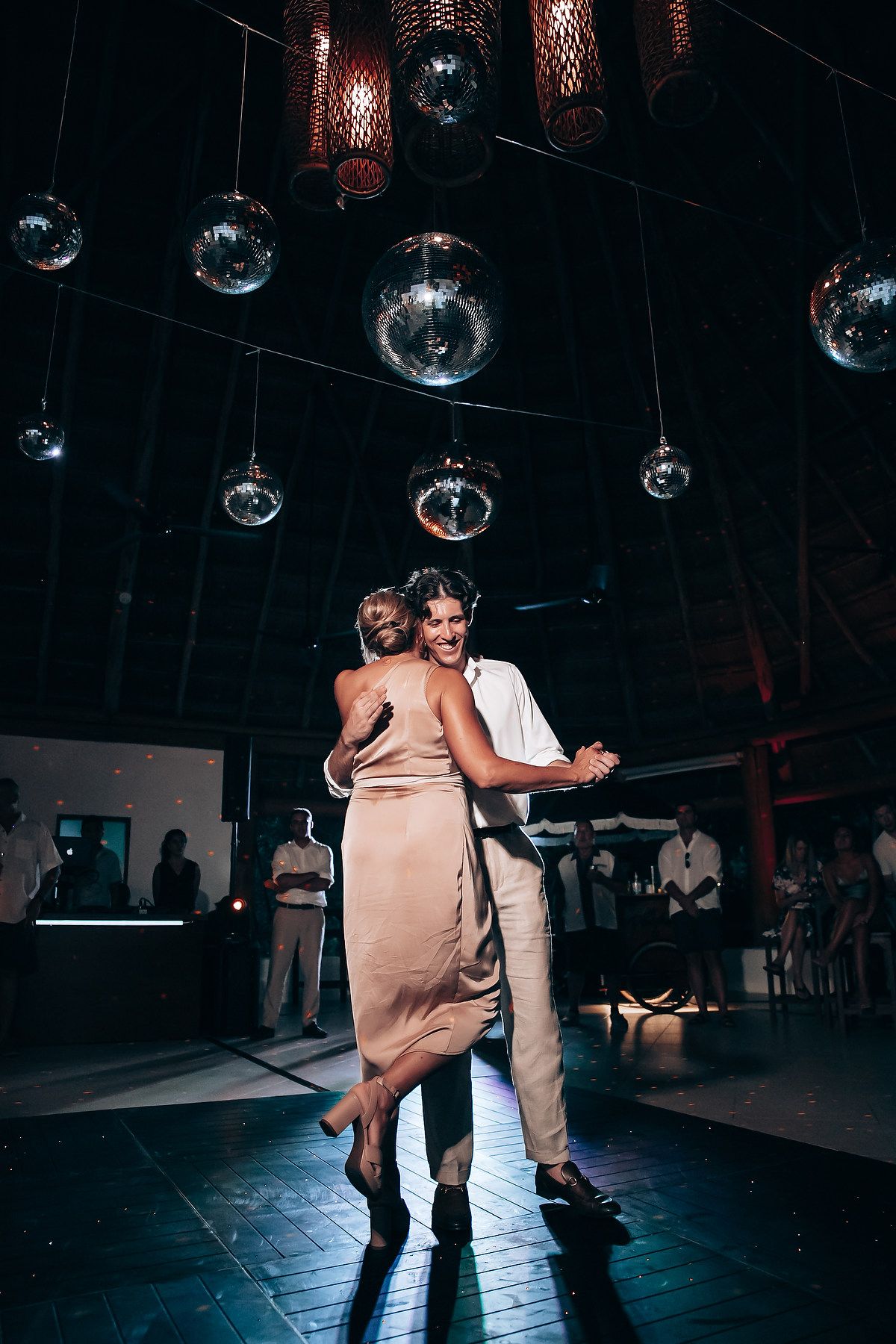 Newlyweds share a joyful dance moment under sparkling disco balls.