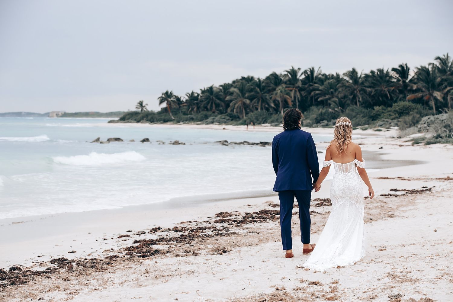 Scenic beach wedding photography session with palm trees and ocean waves in the background.