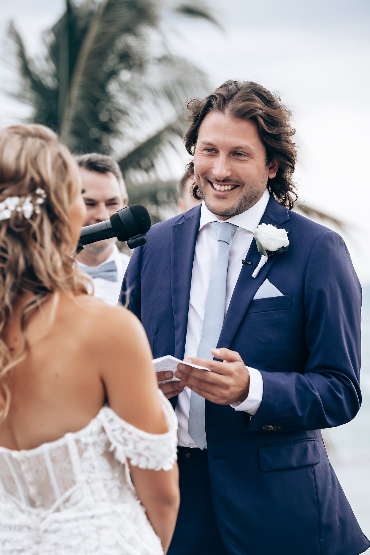 Intimate wedding ceremony moment between couple exchanging vows on a tropical beach deck.