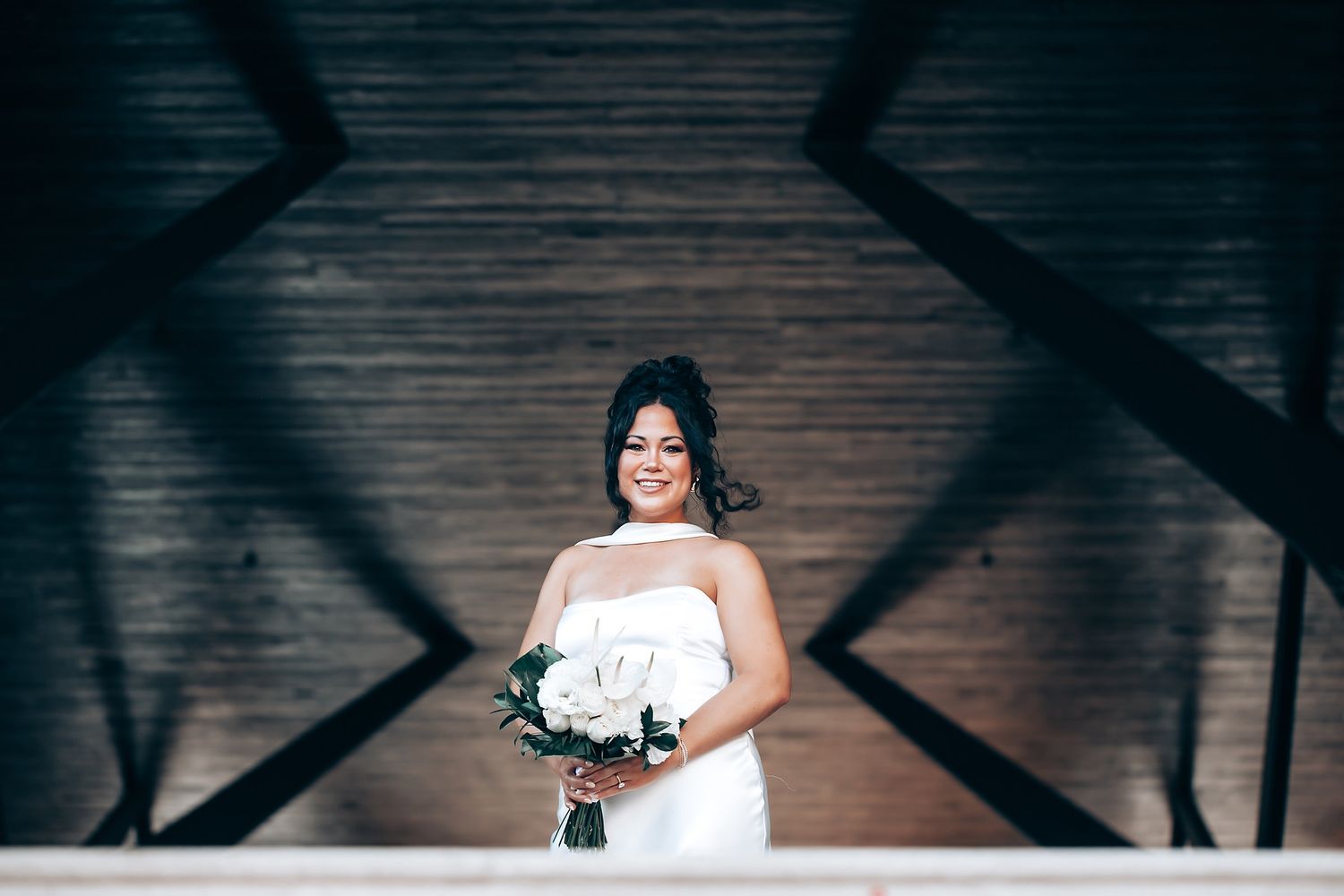 Artistic wedding photography with dramatic lighting and shadows on dark wooden floor.