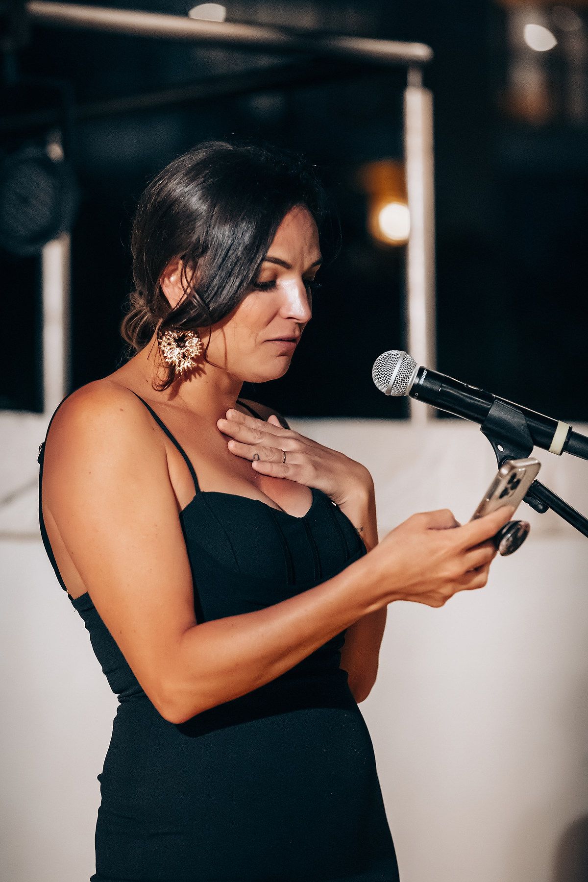 Guest delivers emotional wedding speech into microphone during reception celebration.