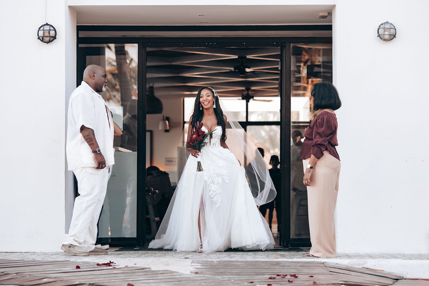 Wedding ceremony preparations at a white-walled venue with guests arriving.
