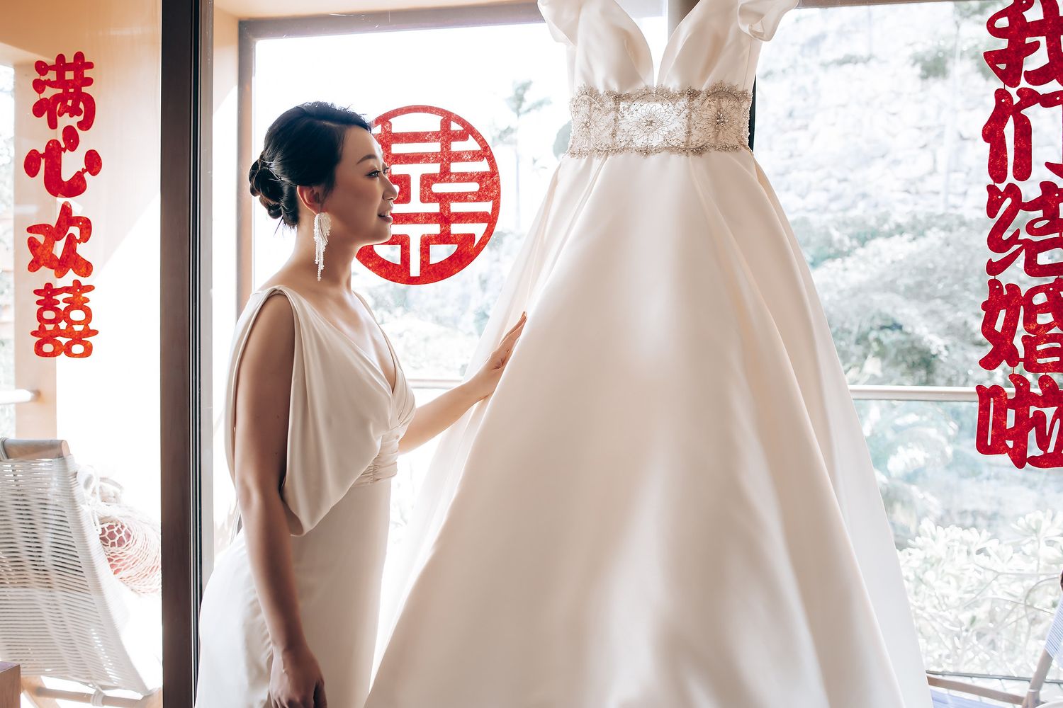 Wedding preparations in a room decorated with traditional Chinese red paper cutouts and symbols.