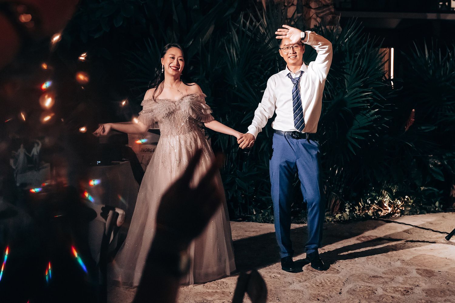 A couple dances together during an evening wedding reception with warm lighting and shadows.