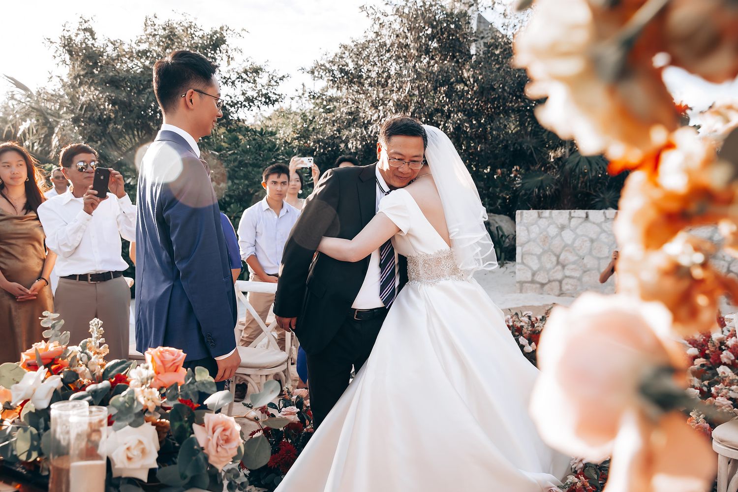 Wedding ceremony scene with peach-colored floral decorations in an outdoor setting.