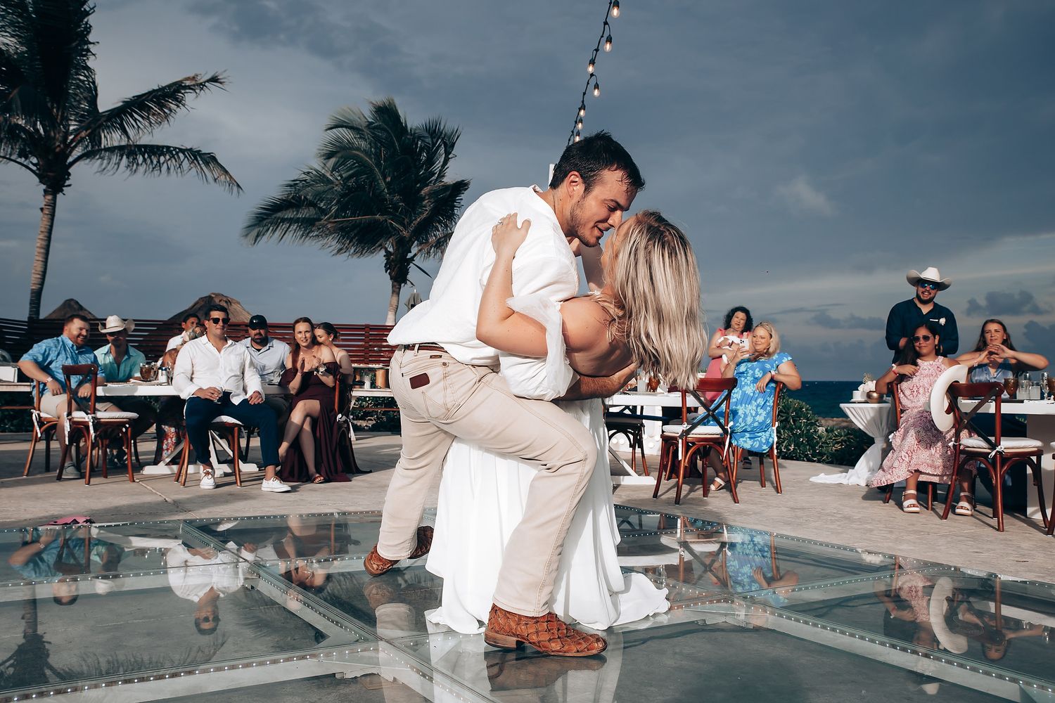 Couples dancing and celebrating at a poolside party with palm trees and blue skies.