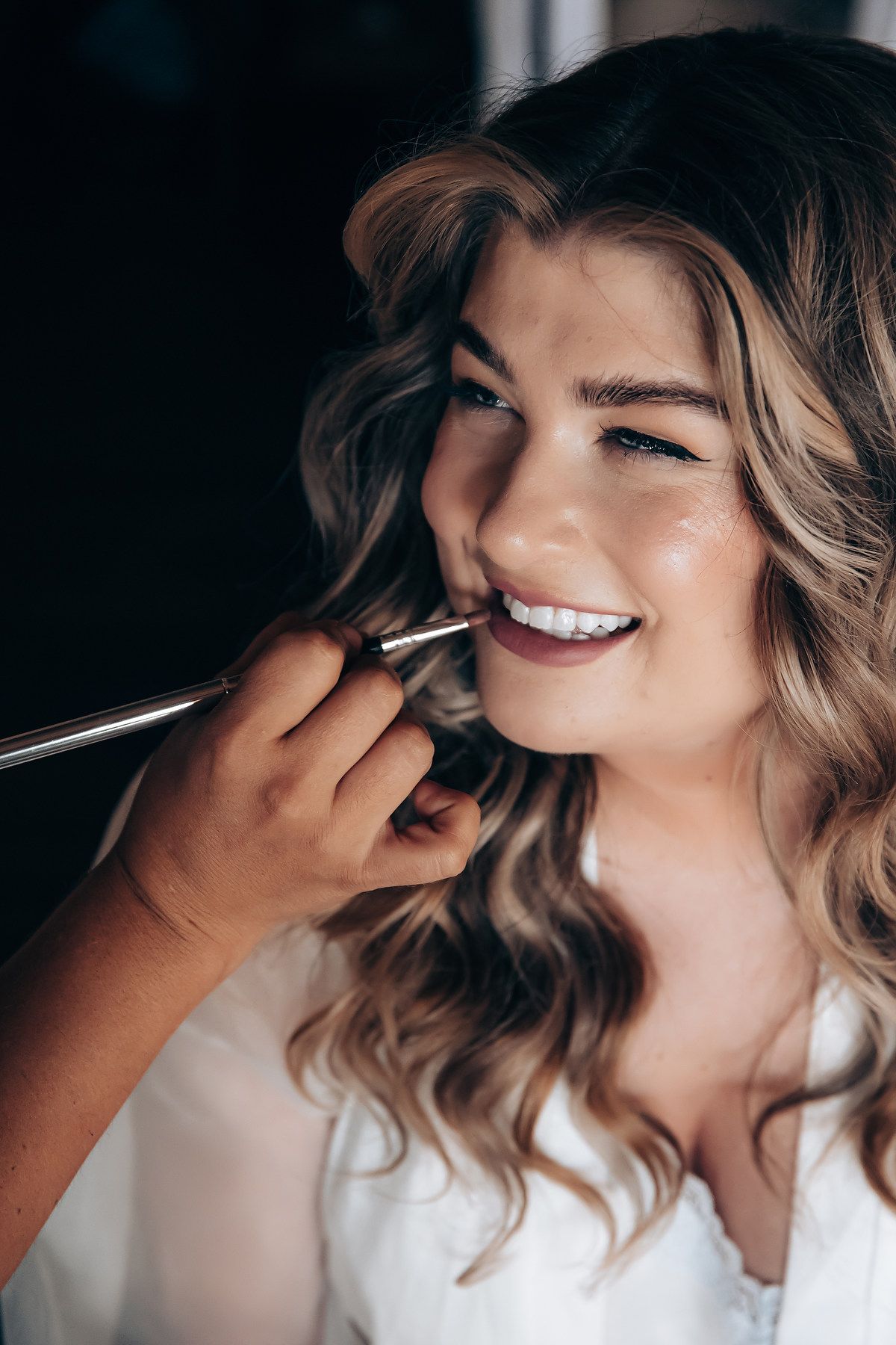 Close-up of makeup application with soft natural lighting.